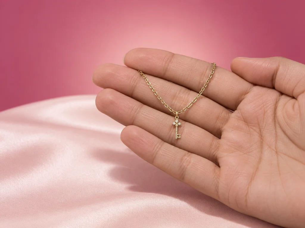 A close studio photograph showing the exact fine gold-tone necklace and tiny vertical key pendant fr