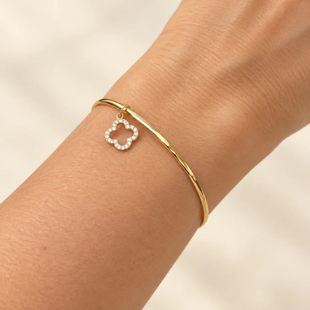 Bracelet trèfle doré porté au poignet en gros plan