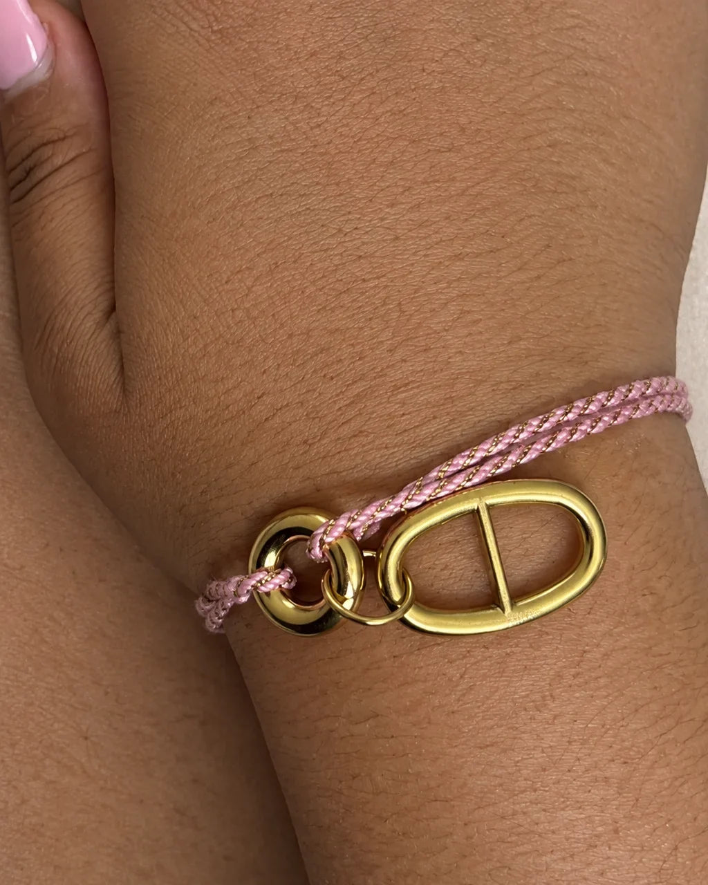 Bracelet cordon rose à anneaux porté en gros plan