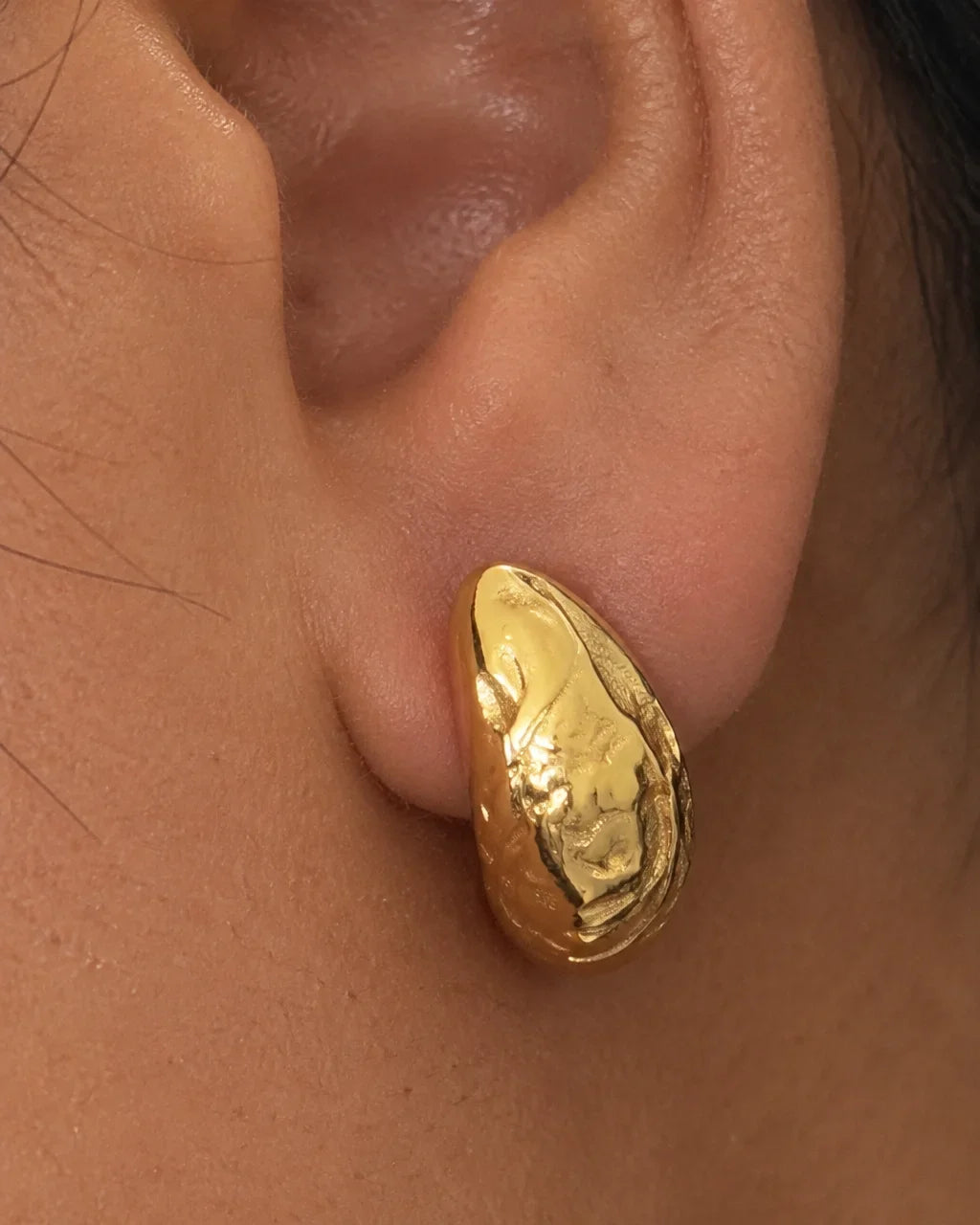 Boucle dorée texturée portée en gros plan